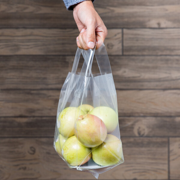 A hand holding a Polypropylene soft loop handle bag of apples.