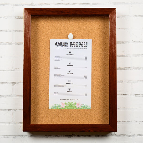A cork bulletin board with a wooden frame and a menu in it.