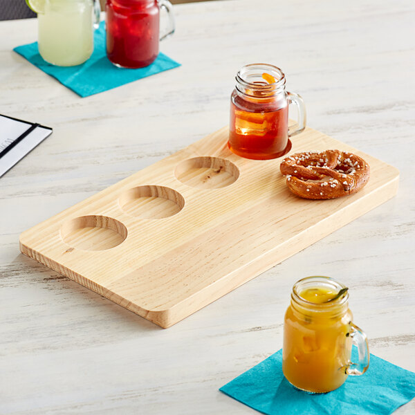 An Acopa natural wood flight tray with drinks and snacks on it.