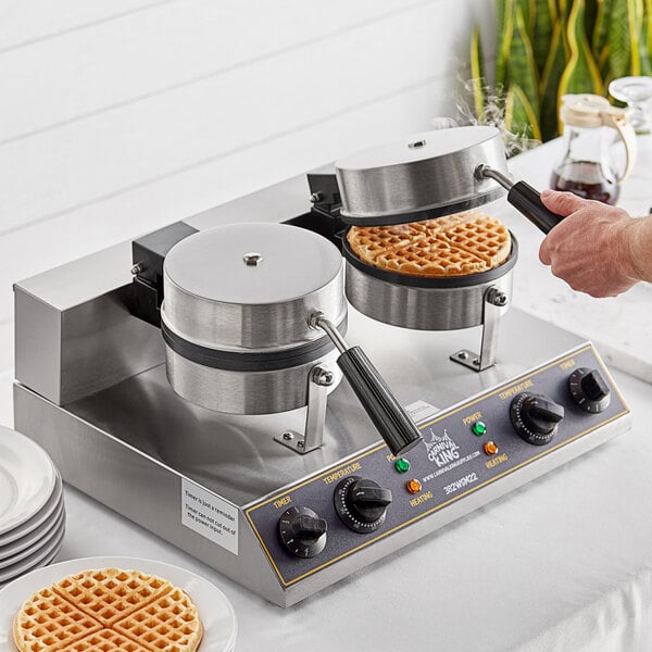 A person using a Carnival King double waffle maker to cook two round waffles.
