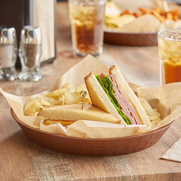 A brown plastic platter holding sandwiches and chips on a table.