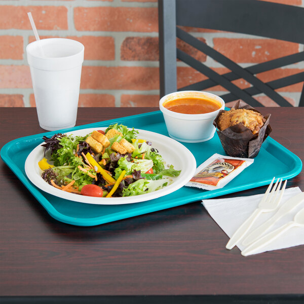 A Vollrath teal plastic fast food tray with a plate of salad and a bowl of soup on it.