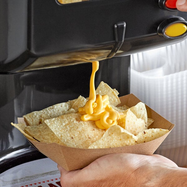 A person pouring Carnival King cheddar cheese sauce on a bowl of chips.