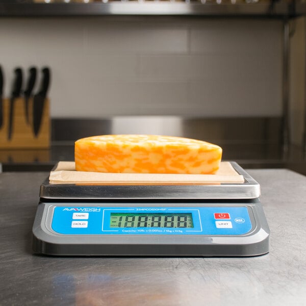 An AvaWeigh digital portion scale on a counter weighing cheese.