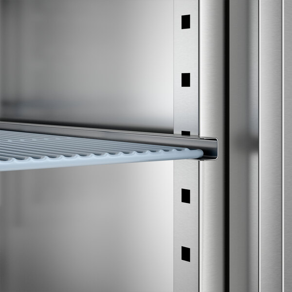A close-up view of an adjustable wire shelf inside a stainless steel reach-in freezer.