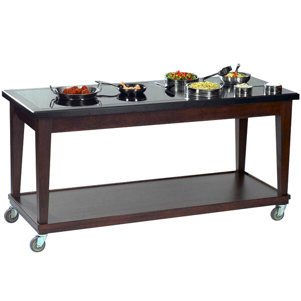 A Bon Chef wood mobile buffet table with a black granite top and food on it.