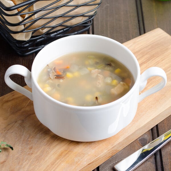 A white Villeroy & Boch La Scala porcelain soup cup filled with chicken and vegetable soup.