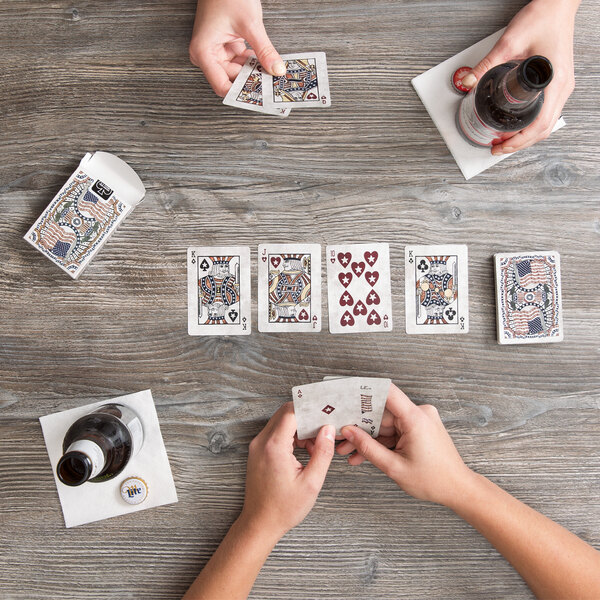 A group of people playing Bicycle American Flag playing cards on a wooden table.