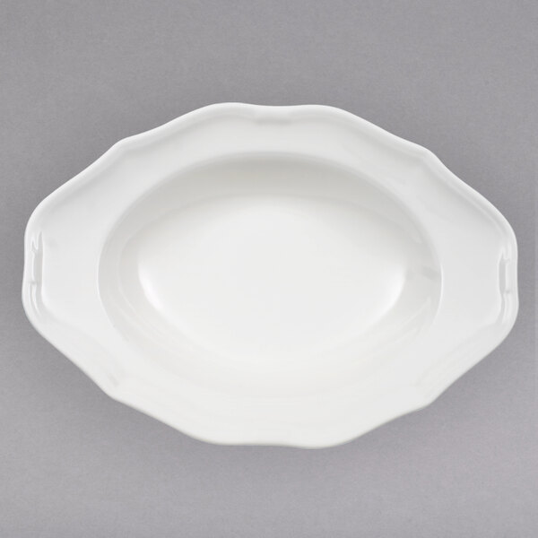 A white porcelain oval deep plate with a scalloped edge.