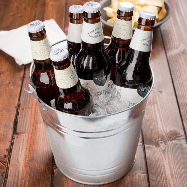 An American Metalcraft galvanized metal bucket filled with beer bottles on a table in a brewery tasting room.