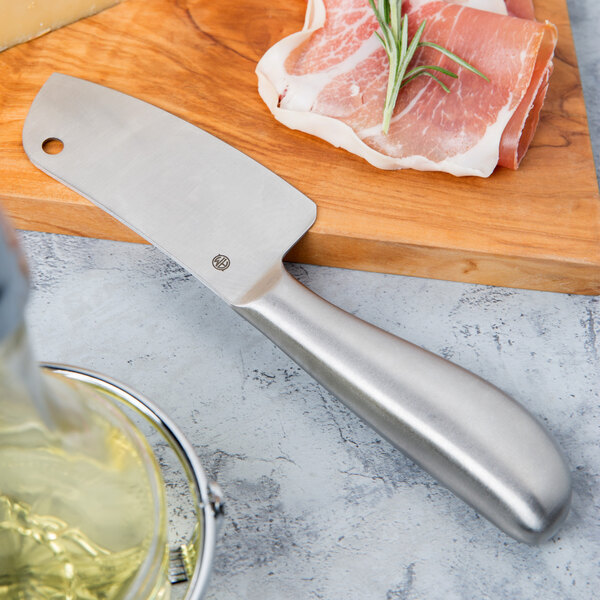 An American Metalcraft stainless steel hard cheese cleaver on a cutting board next to meat.