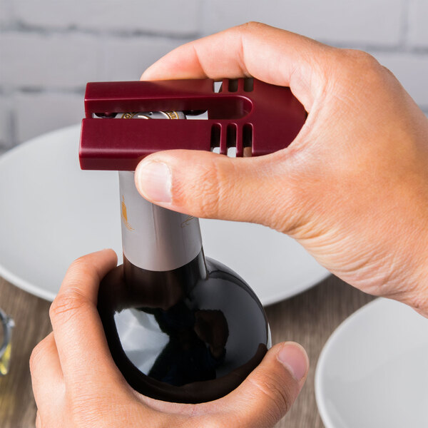 A person using a Franmara burgundy wine foil cutter to open a bottle of wine.