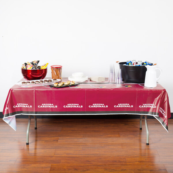 A table with a Creative Converting Arizona Cardinals table cover and food on it.