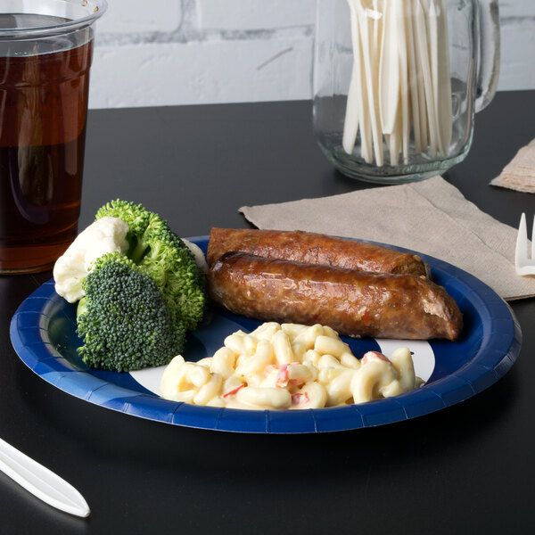 A Creative Converting Indianapolis Colts paper dinner plate with macaroni and cheese, broccoli and sausage on a table.