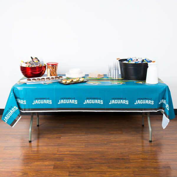 A Jacksonville Jaguars table cover on a table with food.