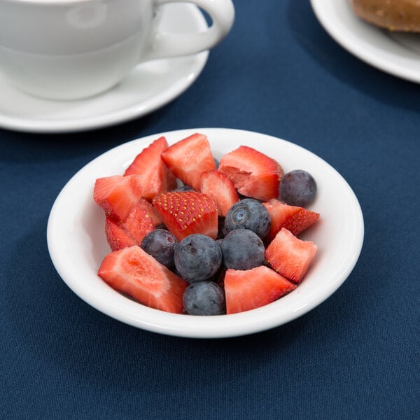 A Tuxton Alaska bright white china bowl with strawberries, blueberries, and a donut.