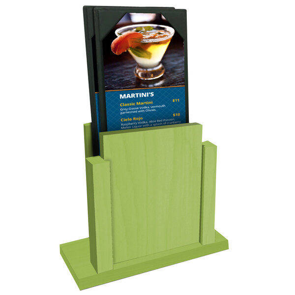 A lime wood Menu Solutions stand holding a menu on a table with a drink.