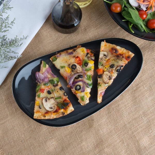 A slice of pizza with vegetables and olives on a black Libbey porcelain tray.