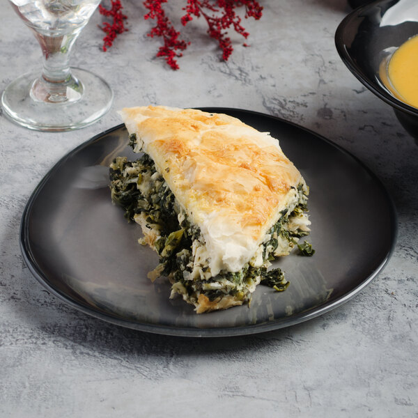 A piece of spinach pie on a Reserve by Libbey Pebblebrook porcelain plate on a table.