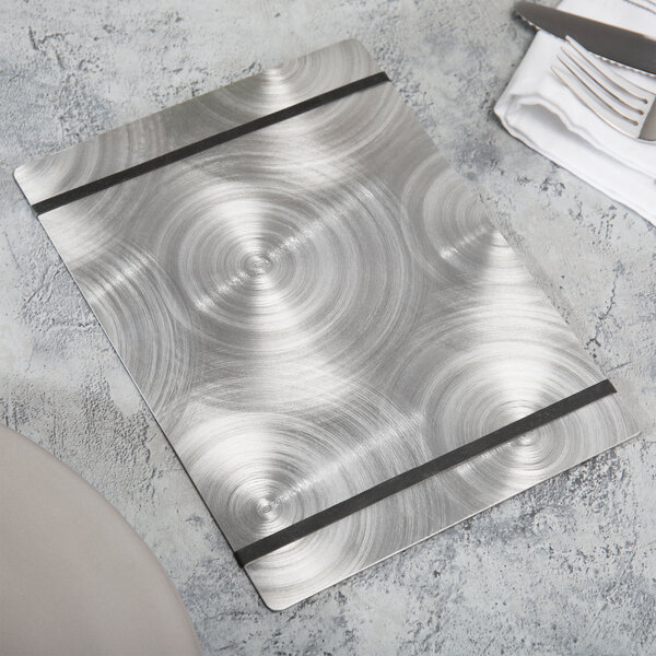 A Menu Solutions Alumitique aluminum menu board with black bands on a table with a white napkin and a knife and fork.