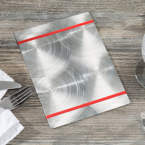 A Menu Solutions Alumitique aluminum menu board with red bands and silverware on a wood surface.
