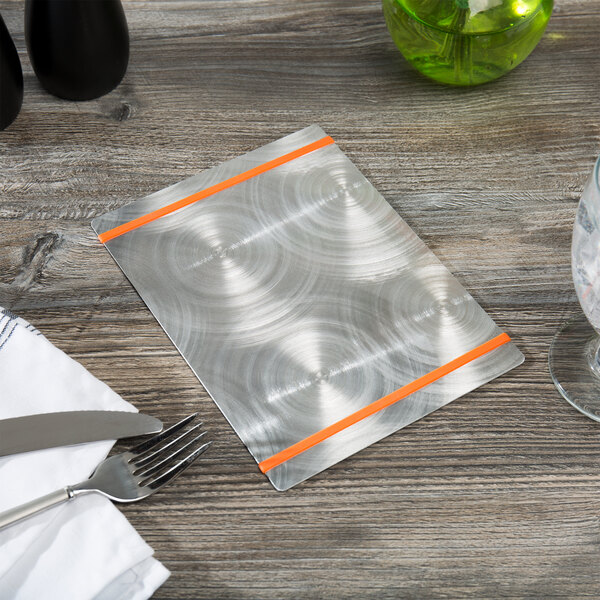 A Menu Solutions Alumitique menu board with orange bands, a fork, and a knife on a table.