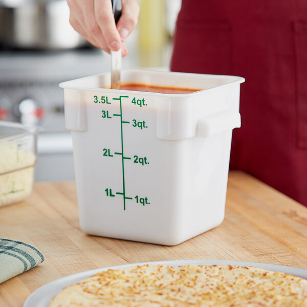 A person measuring out pizza in a white Choice square food storage container.