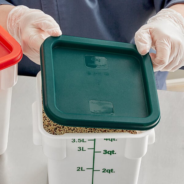 A person in gloves holding a Choice green polypropylene lid over a food container.