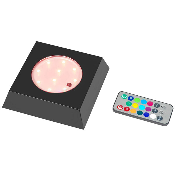 A black square box with a circular LED light inside and a remote control.