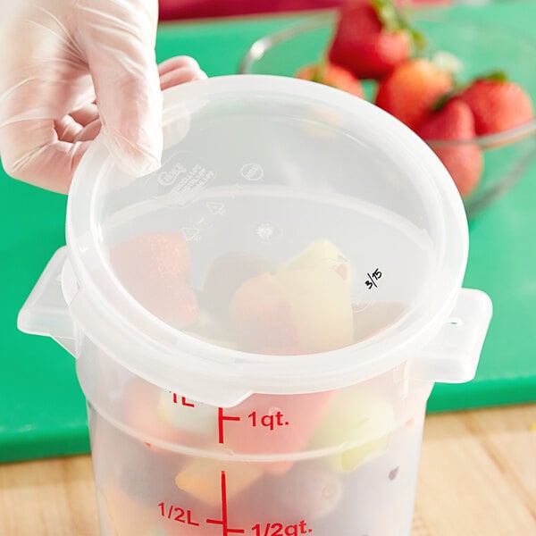 A hand holding a Choice translucent plastic container lid over a bowl of strawberries.