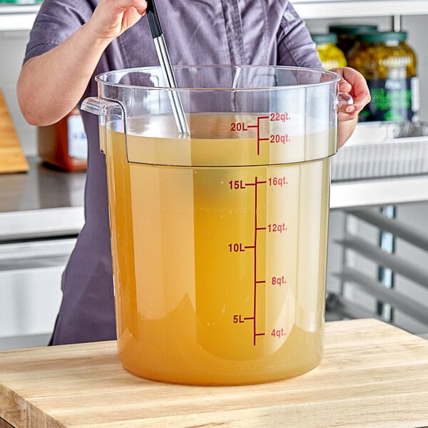 A woman mixing a liquid in a large Choice clear round food storage container.