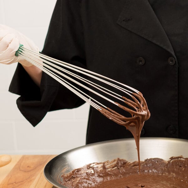 A person using a Vollrath stainless steel French whisk to mix chocolate frosting.