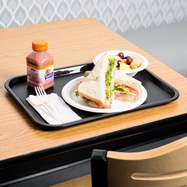 A black plastic fast food tray with a sandwich and bowl of fruit on it.