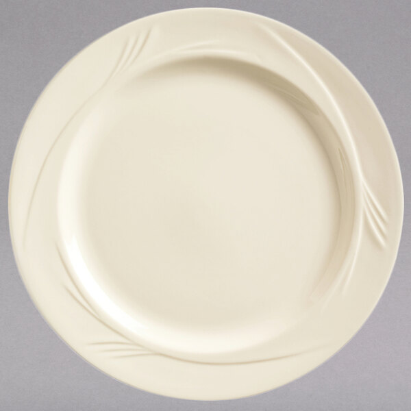 A Libbey round cream white medium rim china plate with swirls on it.