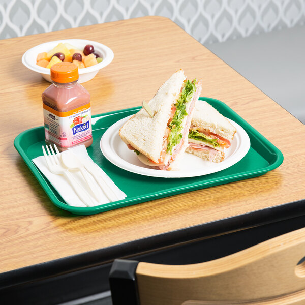 A green plastic Choice fast food tray with a sandwich and a bottle of strawberry banana juice on it.