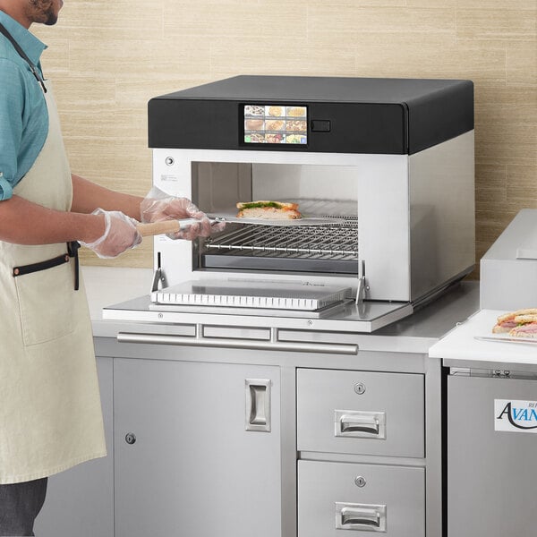 A man using a ACP XpressChef 4i oven to cook food on a tray.