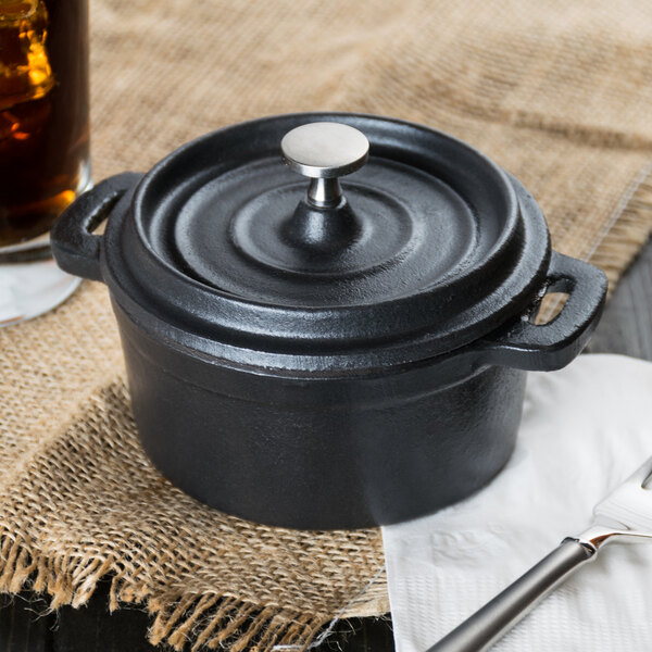 A Libbey black cast iron pot with a lid on a table.