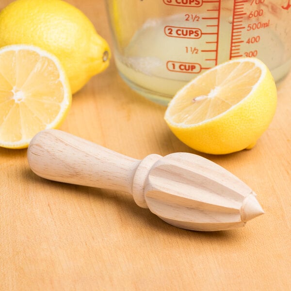 A wooden table with lemons and a Franmara beechwood squeezer.