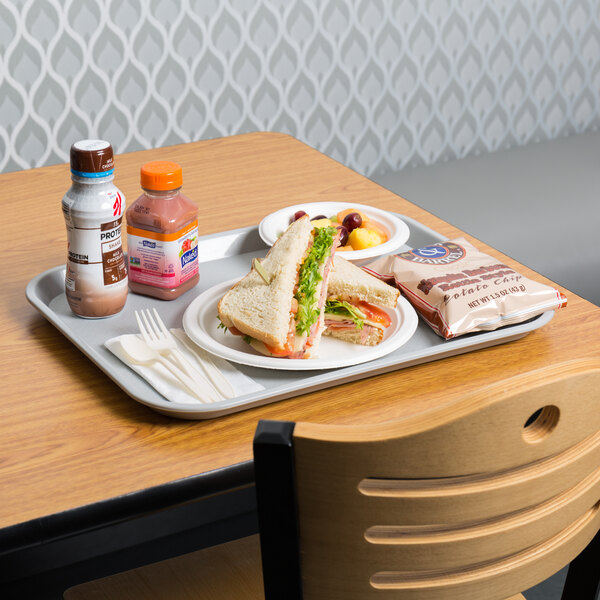A gray plastic fast food tray with a sandwich and other food on it.