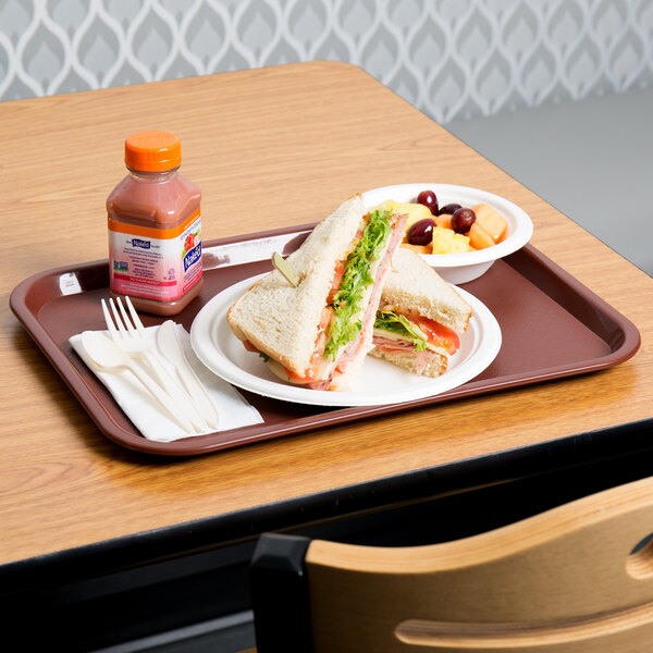 A burgundy plastic fast food tray with a sandwich, bowl of fruit, and a bottle of juice.