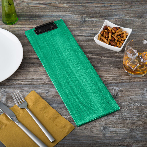 A washed teal wood clipboard on a table with a plate and silverware.
