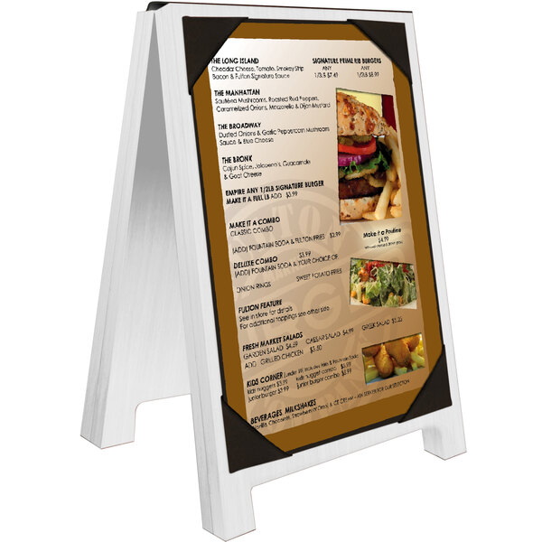 A white wash wood Menu Solutions menu board with picture corners on a table showing a menu.