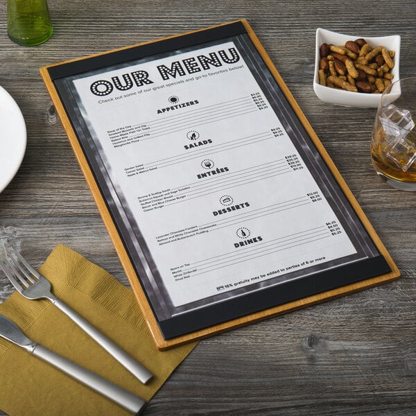 A customizable wood menu board with top and bottom strips on a table with a silver knife and fork.
