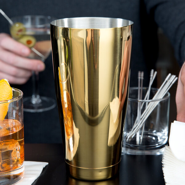 A man using a gold-plated Barfly cocktail shaker to make a drink.