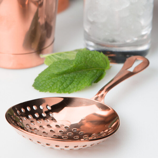 A copper Barfly Julep strainer with a leaf on it.