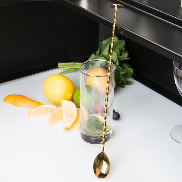 A Barfly gold plated bar spoon in a glass with fruit.