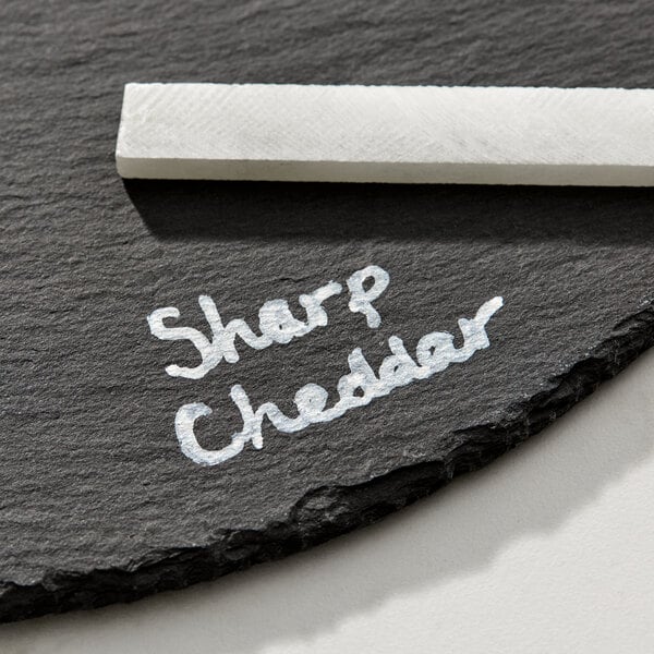 A round black slate tray with a piece of white soapstone chalk resting on it.