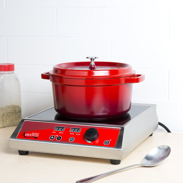 A red GET Heiss Dutch oven with a lid on a stove.