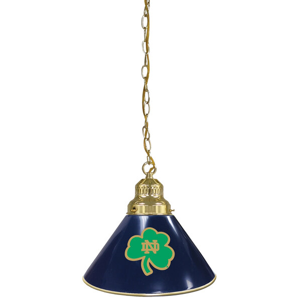 A blue lamp with a brass Notre Dame logo shade featuring a green shamrock.