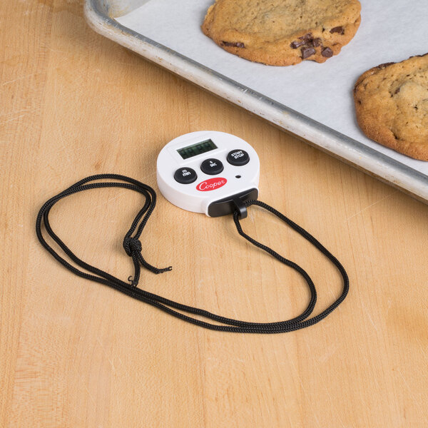 A white Cooper-Atkins digital kitchen timer next to cookies on a tray.